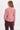 a woman wearing a pink corduroy jacket and berry pants on a white background.
