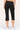 Black cropped cargo pants shown from the back on a model, featuring zippered side cargo pockets and rolled cuffs, paired with white sneakers against a light beige studio background.