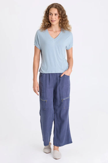 A woman wearing blue twill cargo pants and a light blue short sleeve tee on a white background.