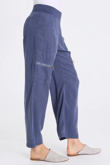 A side view of the blue twill cargo pants with a zippered pocket on each thigh, with an elastic waistband and two side pockets.