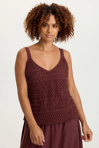 Woman wearing a brown crochet top and skirt on a white background