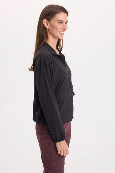 A woman wearing a black active jacket and berry pants on a whit background