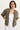 A woman wearing a white tank and a moss green cargo jacket with white pants