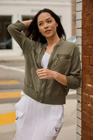 A woman wearing a white outfit with a moss green cargo jacket