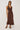 Woman wearing a brown sleeveless dress against a white background
