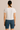 Person wearing a white t-shirt and blue denim shorts on a beige background