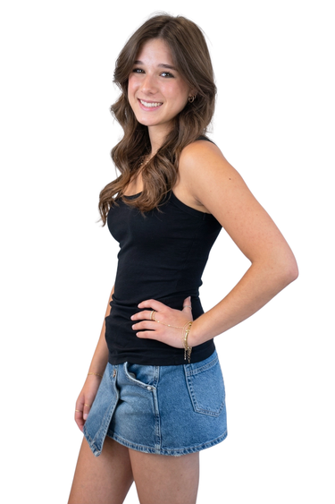 Woman wearing a black tank top and denim shorts on a white background