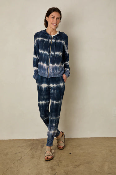 Person wearing a blue tie-dye outfit standing against a plain background