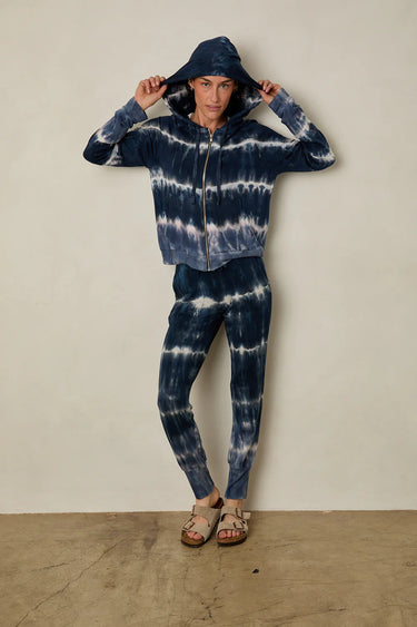 Person wearing a blue and white tie-dye hoodie and pants against a plain background