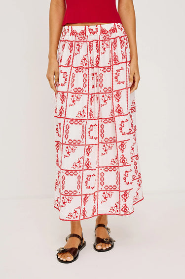 Person wearing a red and white patterned skirt on a plain background