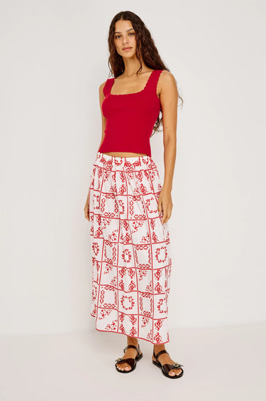 Woman wearing a red top and patterned skirt on a white background