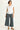 Woman wearing a white blouse and gray wide-leg pants on a white background