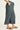 Person wearing teal pleated pants on a white background