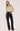 A woman wearing a black polka dot and cream blouse with black jeans on a white background.