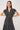 Woman wearing a black dress with white patterns against a plain background