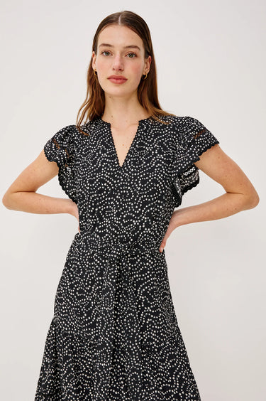 Woman wearing a black dress with white patterns against a plain background