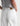 White pants with a brown label worn by a person on a white background