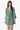 woman wearing green floral dress with a white background