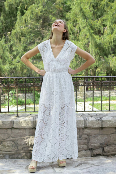 woman wearing a white maxi lace dress in front of a fence