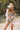 woman wearing a onepiece striped swimsuit on a beach with a hat and white shirt coverup