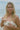 Woman on a beach holding a jar of sunscreen