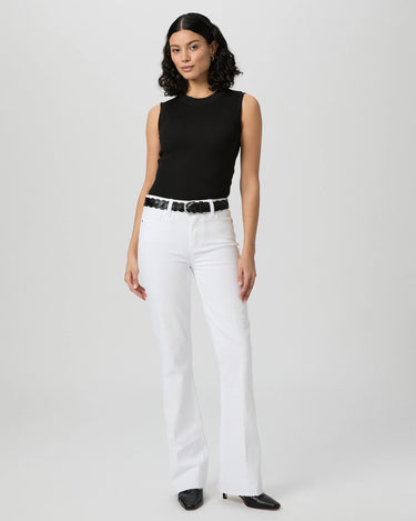 Woman wearing a black sleeveless top and white pants on a plain background