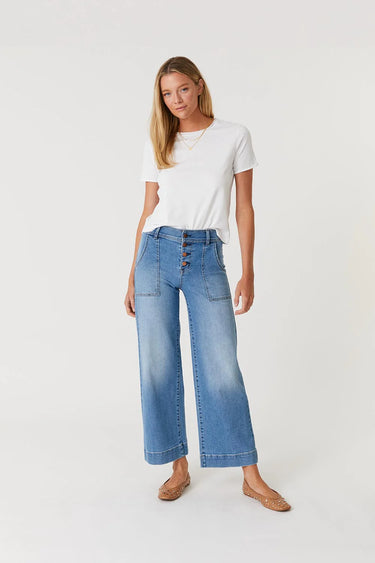 woman in white tee with button fly wide leg jeans on a white background