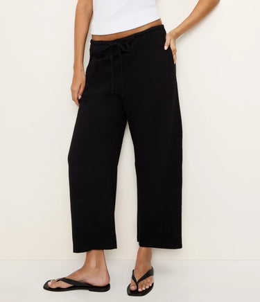 Person wearing black wide-leg pants on a white background