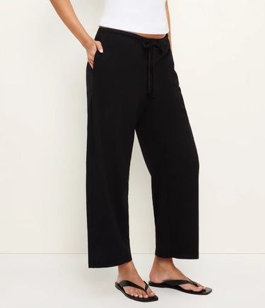 Person wearing black wide-leg pants with a white background