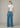Woman wearing a white t-shirt and blue jeans on a plain background