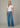 Woman wearing a white top and blue jeans against a neutral background