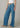 Person wearing blue jeans with a white top on a plain background