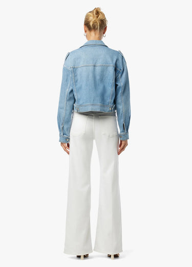 Person wearing a blue denim jacket and white pants on a white background