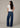 Woman wearing a white t-shirt and blue jeans on a beige background