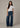 Woman wearing a white t-shirt and blue jeans on a plain background