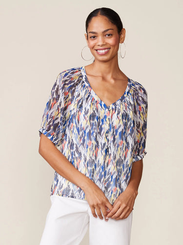 Woman wearing a colorful patterned blouse against a plain background