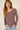 Woman wearing a long-sleeve mauve top against a beige background