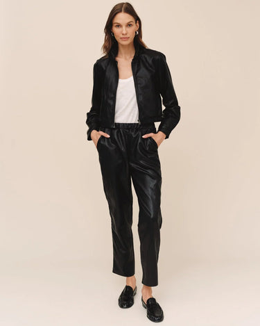 Model wearing Bella Dahl black faux leather pull-on trousers with matching black jacket, white tank top and loafers, showing the ankle-length straight-leg fit.