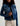 Cropped medium-blue denim workwear jacket with adjustable waist tabs, chest flap pockets, and welt pockets.