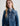 Woman wearing a blue denim jacket over a gray turtleneck on a light gray background
