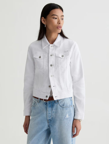 Person wearing a white denim jacket and light blue jeans on a plain background