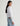 Woman wearing a white shirt and blue jeans on a plain background
