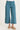Teal capri pants worn by a person on a white background