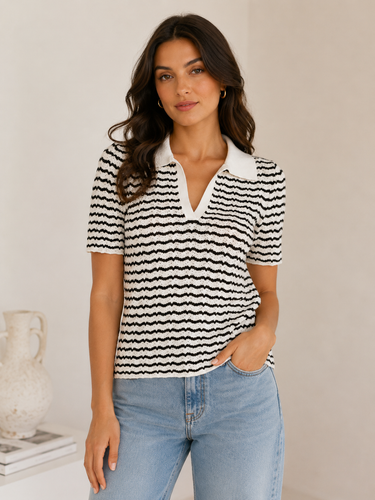 Woman wearing a black and white striped polo shirt with a plain background