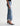 A side-profile view of a model wearing light-wash blue cropped flare jeans with rolled cuffs, paired with black slingback heels, against a plain white studio background.