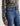 A woman wearing mid-rise medium blue wash straight leg denim with a distressed hem, fading, and gold stitching on a white background.