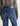 A woman wearing mid-rise medium blue wash straight leg denim with a distressed hem, fading, and gold stitching on a white background.