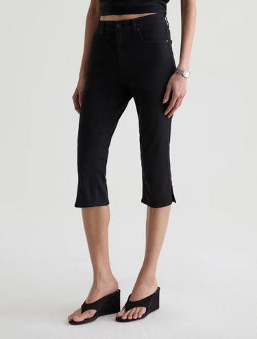 Person wearing black capri pants on a white background