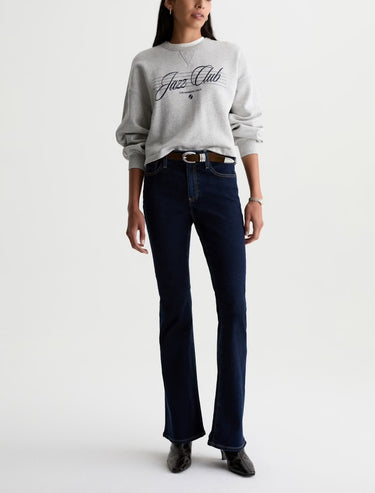 Person wearing a gray sweatshirt with 'Jazz Club' text and dark blue jeans on a white background