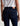 Person wearing dark blue jeans with a visible brand logo on a plain background